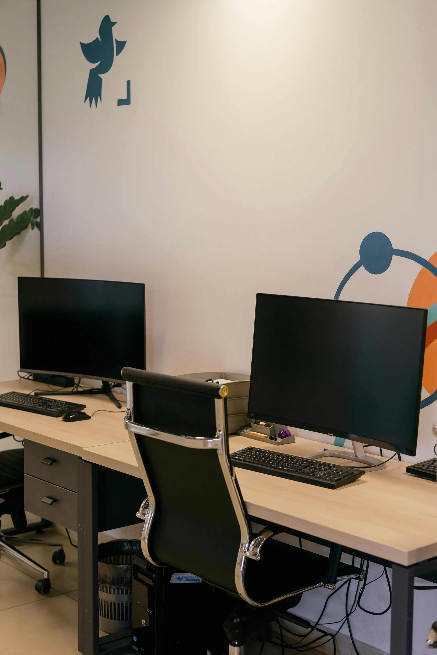 Empty modern office space with two desks, monitors, and stylish chairs.